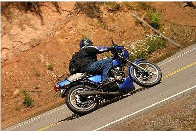 1985 Ford LTD Crown Victoria - A rider navigates a scenic road on a blue motorcycle.