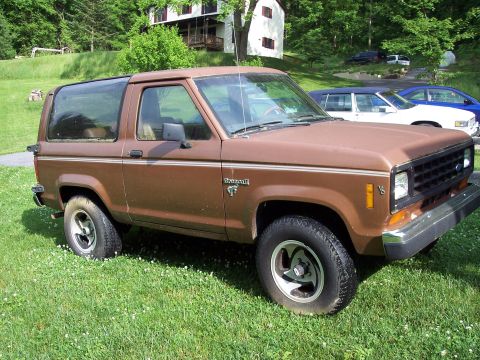 1986 Ford Bronco II - This 1986 Ford Bronco II is seen parked on a grassy lawn with other vehicles in the background.