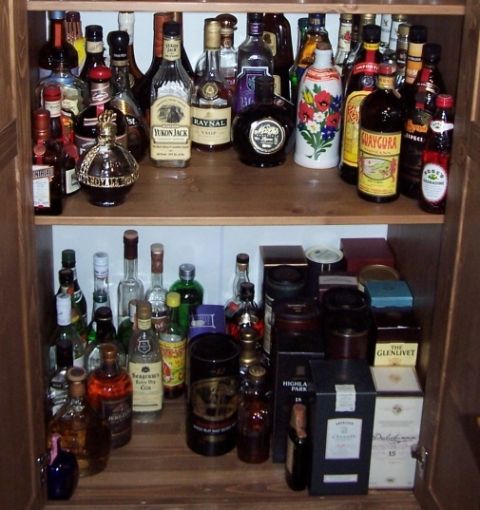 1990 Ford Bronco - A well-stocked liquor cabinet displays a variety of bottles and boxed spirits on two shelves.