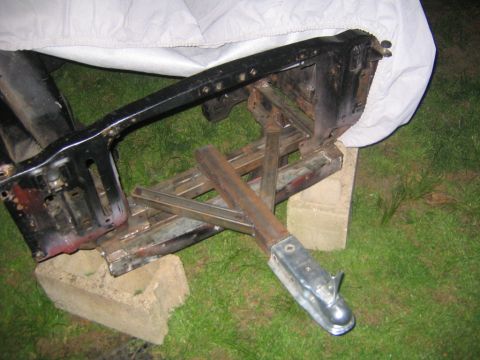 1978 Ford Bronco - A fabricated trailer tongue welded from square tubing with a zinc-plated coupler, bolted onto a cut-down black vehicle frame section restin…