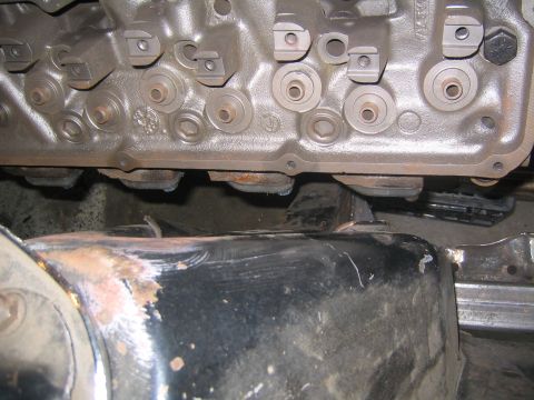 1978 Ford Bronco - Close-up of a cast metal drivetrain casting with numerous machined bolt bosses, retaining clips and cast identification marks, seen from be…