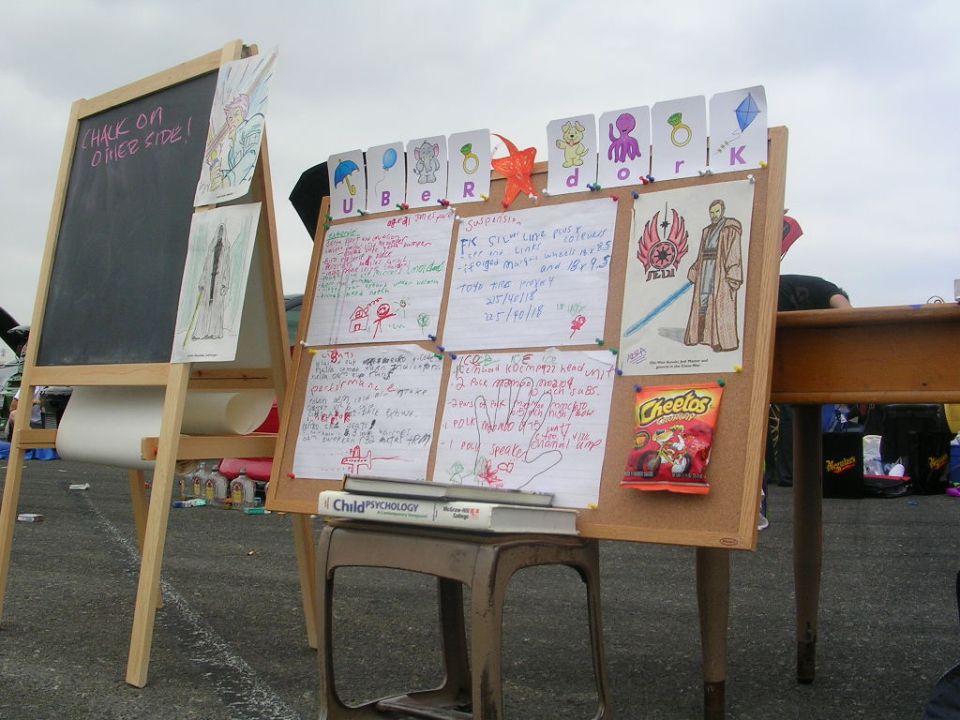 Bulletin board with drawings, writings, and a bag of Cheetos, next to a chalkboard easel