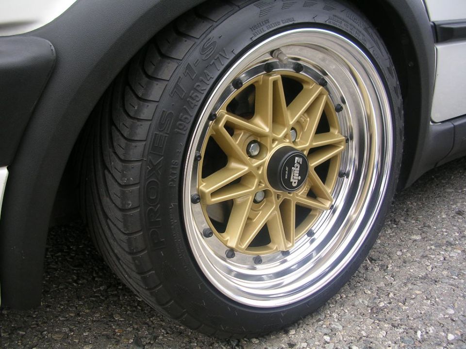 Close-up of a gold multi-spoke wheel with a black center cap that says "Equip". Tire has "PROXES T1-S" text