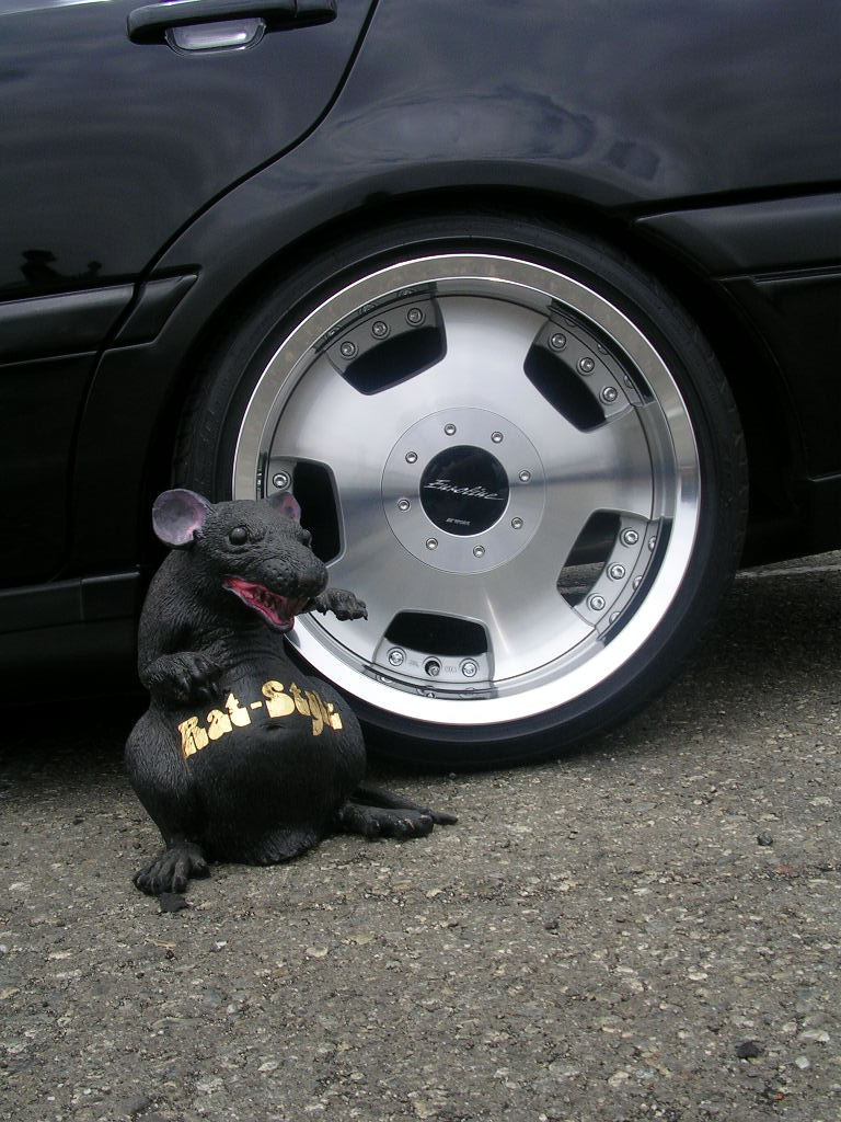 Deep-dish polished multi-piece wheel on a lowered black car with a Rat-Style rat statue