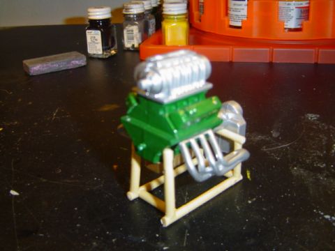 1979 Ford Bronco - A model engine, painted green and silver, sits on a stand with hobby paint bottles nearby.