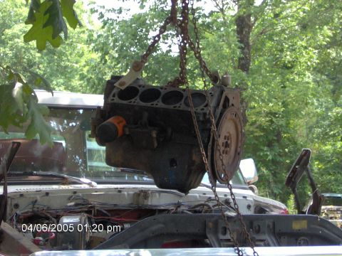 1978 Ford Bronco - An engine is being removed from a white vehicle, with chains holding it aloft.