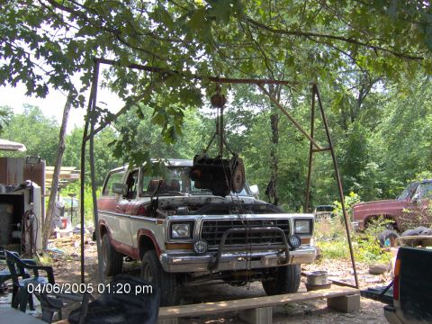 1978 Ford Bronco - A 1978 Ford Bronco is parked outdoors with its engine being hoisted out for maintenance or repair.