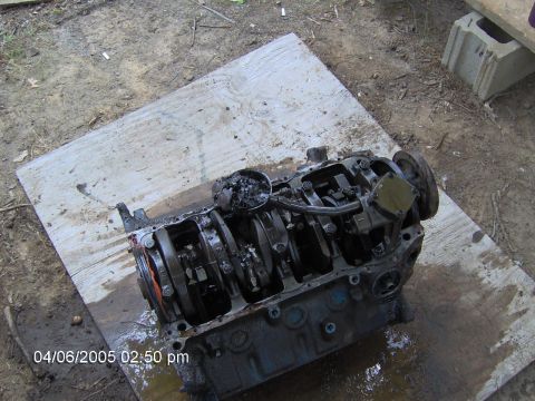 1978 Ford Bronco - The engine block is disassembled and resting on a piece of plywood on the ground.