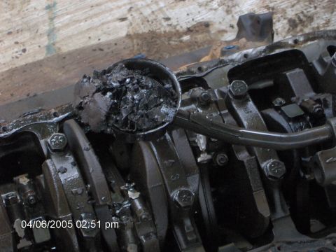 1978 Ford Bronco - A close-up view of an engine's oil pan, heavily contaminated with sludge, obscuring internal components.