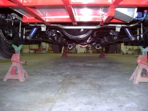 1994 Ford Bronco - The underside of a vehicle is visible, supported by red jack stands in a garage.