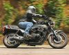 1985 Ford LTD Crown Victoria - Rider on a motorcycle in motion on a road with foliage.