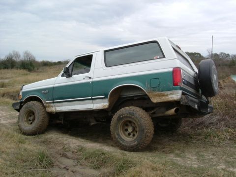 1996 Ford Bronco - This Ford Bronco is shown from a three-quarter front view, navigating a dirt and mud path.