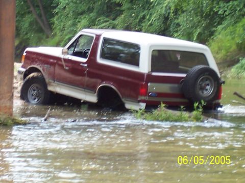 1990 Ford Bronco - 1990 Ford Bronco navigating a water crossing on a dirt trail.