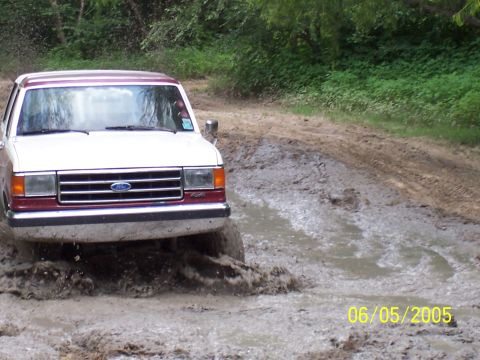 1990 Ford Bronco - This 1990 Ford Bronco navigates a muddy trail, kicking up water and dirt.