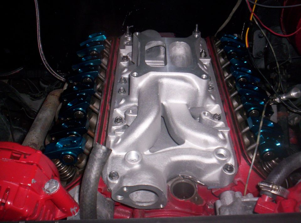 Aluminum intake manifold on a red engine block with blue roller rockers