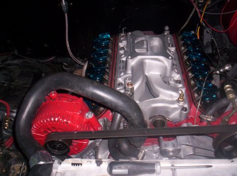1989 Ford Bronco II - Close-up view of an engine bay a red alternator, silver intake manifold, and blue valve covers.