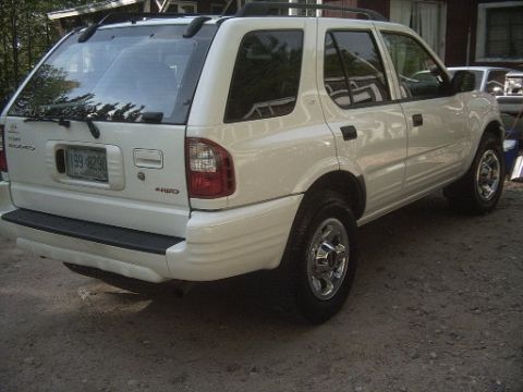 2000 Isuzu Rodeo - Rear view of a white 2000 Isuzu Rodeo parked on a gravel surface.