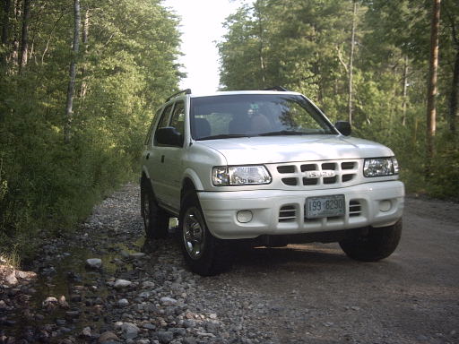 2000 Isuzu Rodeo parked on a gravel road with trees in the background. License plate reads 199-8290