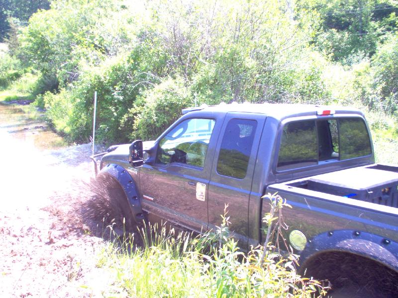 Dark grey pickup truck driving through mud, splashing water