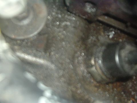 1993 Ford Taurus - This image shows a close-up view of an engine component, bolts and accumulated grime.