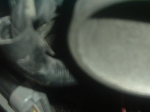 1993 Ford Taurus - A close-up view of a vehicle's engine bay shows a hose connected to a metal part.