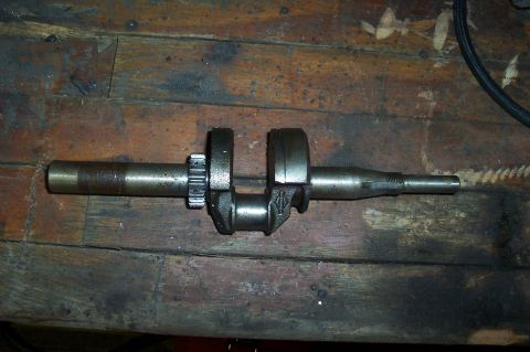1994 Ford F-150 - A crankshaft is shown resting on a weathered wooden surface.