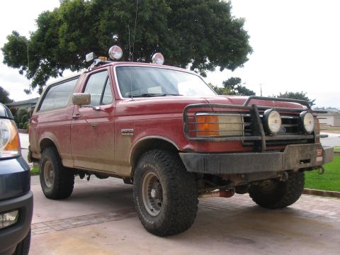 1989 Ford Bronco - This red 1989 Ford Bronco is equipped with a brush guard and auxiliary lights, suggesting it's ready for off-road adventures.