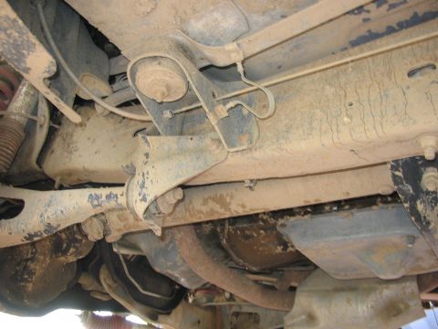 1989 Ford Bronco - The underside of a vehicle shows its suspension and exhaust system, covered in dirt and grime.