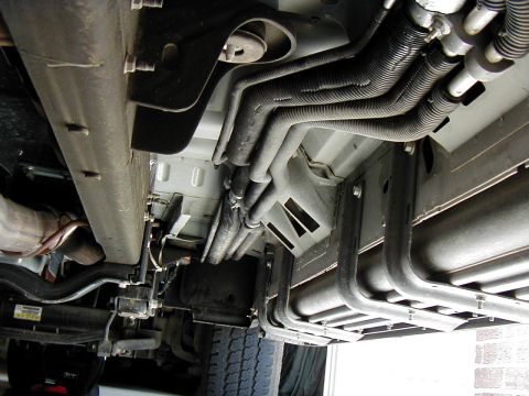 2002 Ford Excursion - The underside of a vehicle reveals a complex network of hoses and structural components.