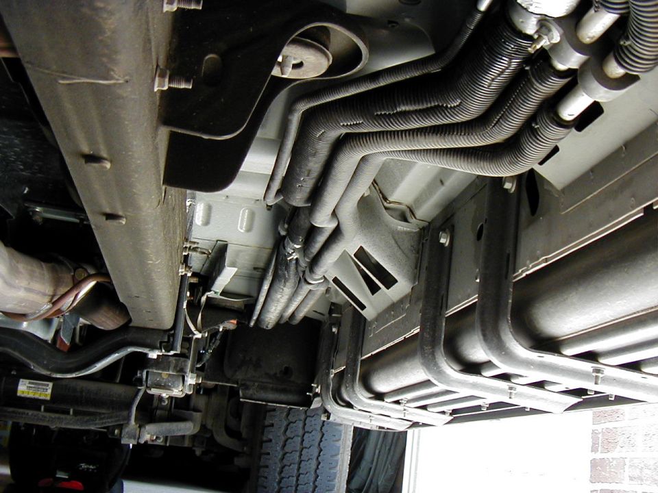 Vehicle undercarriage with metal lines, hoses, and a large tank
