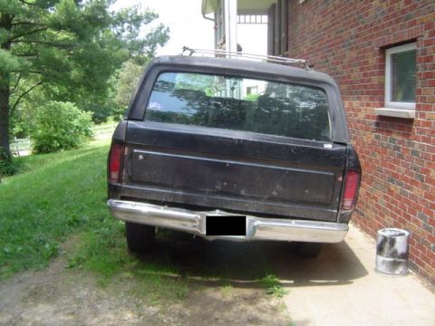 1979 Ford Bronco - This black Ford Bronco is parked on a gravel driveway beside a brick house.