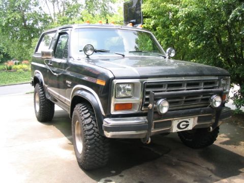 1986 Ford F-150 - This black Ford Bronco, likely from the early 1980s, is equipped with large off-road tires and a heavy-duty front bumper.