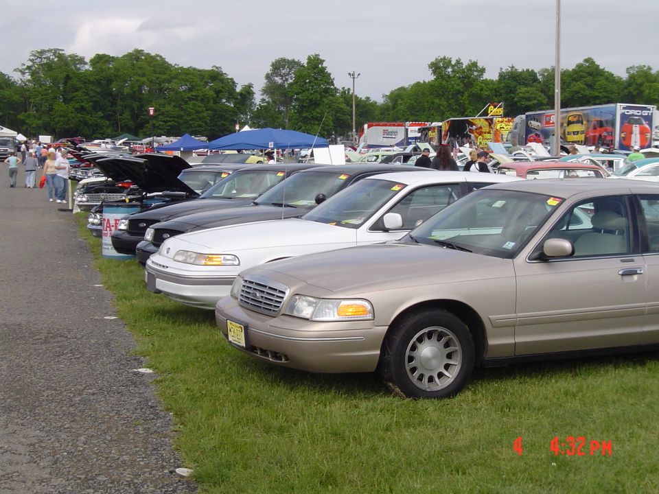 Tan 1998 Ford Crown Victoria, 3/4 front view, parked in a row at an outdoor event