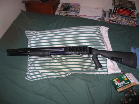 1995 Ford Bronco - A black pump-action shotgun rests on a striped pillow, with a box of 12 gauge buckshot nearby.