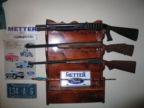 1995 Ford Bronco - A collection of firearms is displayed on a wooden rack, accompanied by automotive memorabilia.