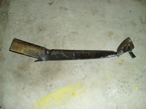 1993 Ford Taurus - A bent metal subframe part lies on a concrete floor, showing signs of wear and damage.