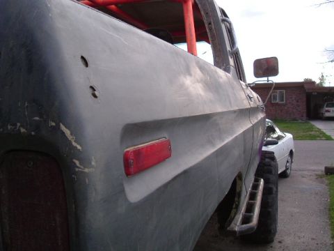 1979 Ford Bronco - A gray pickup truck with a red roll cage and aftermarket bumper is parked next to a white car.