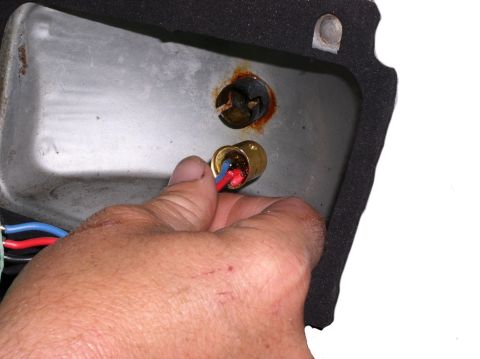 1978 Ford Mustang II - A hand works on a vehicle's taillight assembly, connecting wires to a bulb socket.