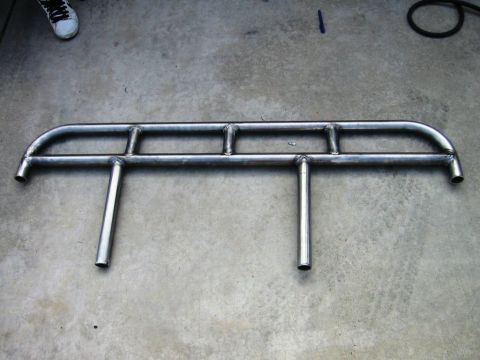 1988 Ford Bronco - A pair of custom-fabricated metal rock sliders are laid out on a concrete surface.