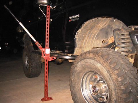 1988 Ford Bronco - A black SUV, identified as a 1988 Ford Bronco by its badge, is shown with a hi-lift jack positioned beside its rear wheel.