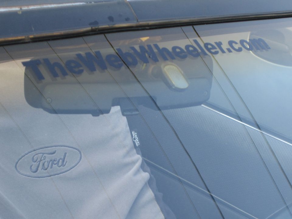 Ford logo on shirt reflected in rear window with TheWebWheeler.com sticker