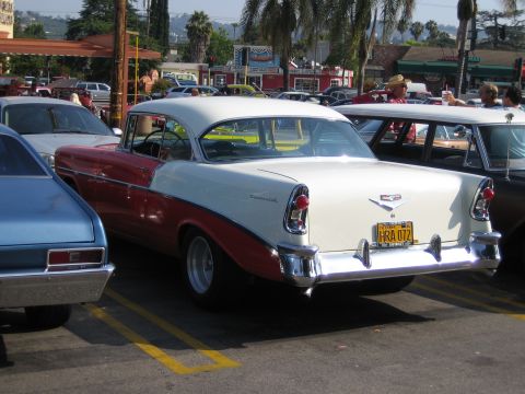 1985 Ford Mustang - Two-tone 1956 Chevrolet sedan parked in a lot with other vehicles.