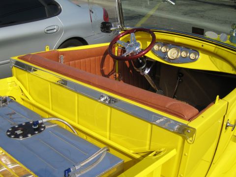 1985 Ford Mustang - The interior of a yellow hot rod features brown upholstered seats, a wooden steering wheel, and a dashboard with multiple gauges.