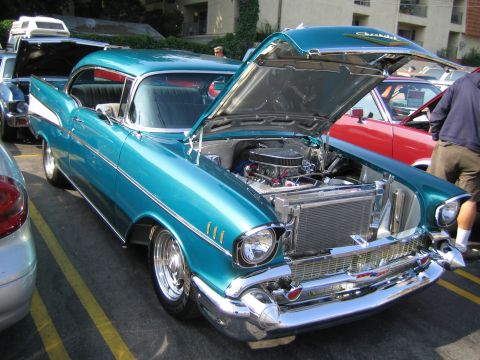 1985 Ford Mustang - Teal 1957 Chevrolet Bel Air at a car show, hood open to display the engine.