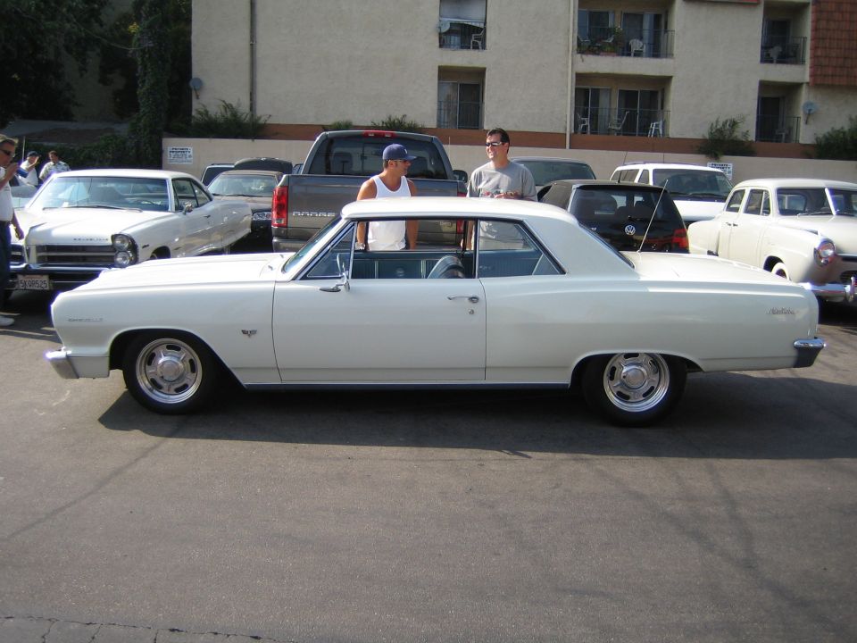 White 1964 Chevelle Malibu coupe parked, two guys standing by it
