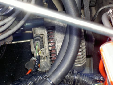 1956 Ford F-100 - Close-up view of an alternator with connected hoses and wiring, showing engine components.