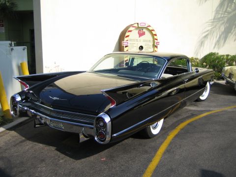 1985 Ford Mustang - Rear view of a black 1959 Cadillac Eldorado parked next to a jukebox.