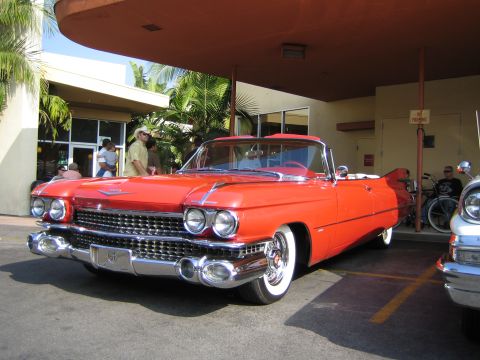 1985 Ford Mustang - Classic red 1959 Cadillac Eldorado convertible parked outdoors with people in the background.