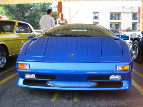 1985 Ford Mustang - A blue Lamborghini Diablo is parked next to a yellow Ford Mustang, viewed from the front.
