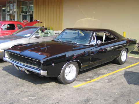 1985 Ford Mustang - A black 1968 Dodge Charger is parked next to other vehicles, with a yellow line marking its parking space.